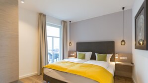 A modern hotel room with a large bed, bedside tables, a window with curtains, and a view of the outside.