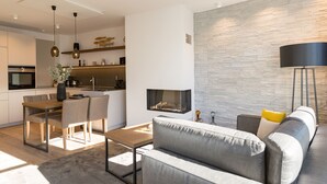 A modern living room with a grey sofa, a wooden coffee table, and a fireplace.