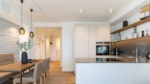 Een moderne keuken met witte kasten, een centraal eiland en hanglampen.