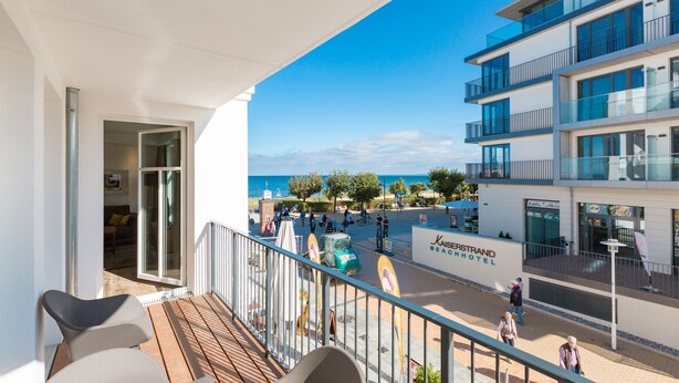 Een balkon met uitzicht op het strand en hotelgebouwen.