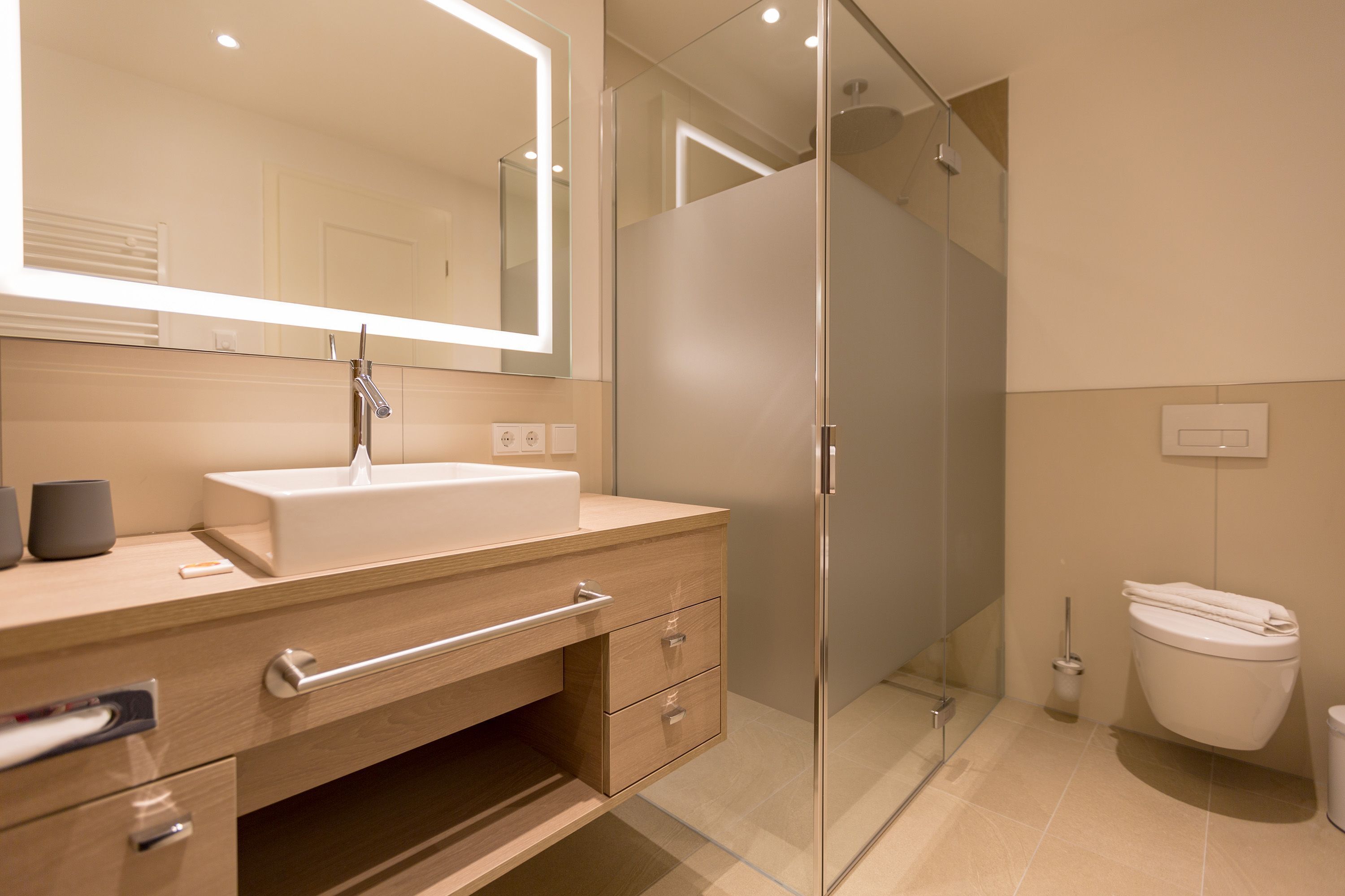 A modern bathroom with a glass shower enclosure, a white sink with a mirror, and a toilet.