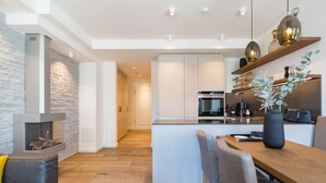 A modern kitchen with a central island, built-in appliances, and a stone accent wall. - Beachhouse Bansin, app. 04 (Heringsdorf)