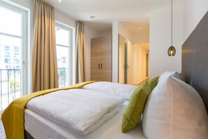 Ein Hotelzimmer mit Bett, Vorhängen, einem Spiegel und Blick ins Freie.