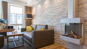 A modern living room with a stone wall, a sofa with cushions, a coffee table, and a fireplace. - Beachhouse Bansin, app. 04 (Heringsdorf)
