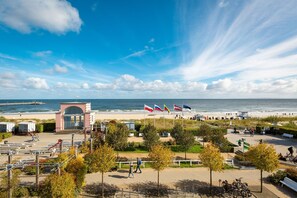 Uma orla costeira com praia, bandeiras e um pequeno pavilhão.