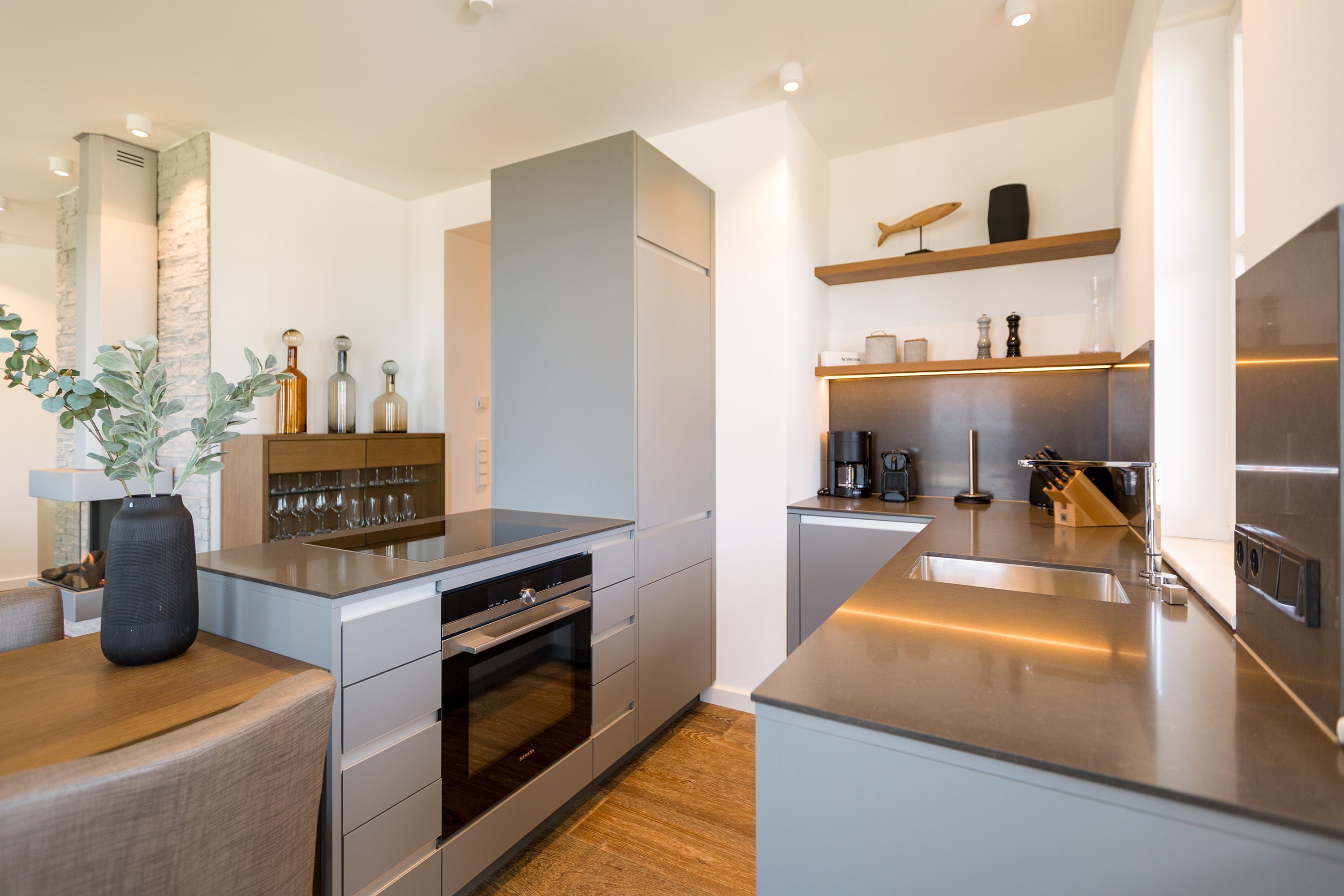 A modern kitchen with stainless steel appliances, a built-in oven, and a large island with a sink.