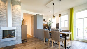 A modern living room with a fireplace, dining area, and kitchen. - Beachhouse Bansin, App. 10 (Heringsdorf)
