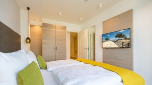 A modern hotel room with a large bed, a wardrobe, and a painting on the wall. - Beachhouse Bansin, App. 01 (Heringsdorf)