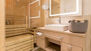 A modern bathroom with a wooden sauna, a large mirror, and a sink with a stone basin. - Beachhouse Bansin, App. 01 (Heringsdorf)