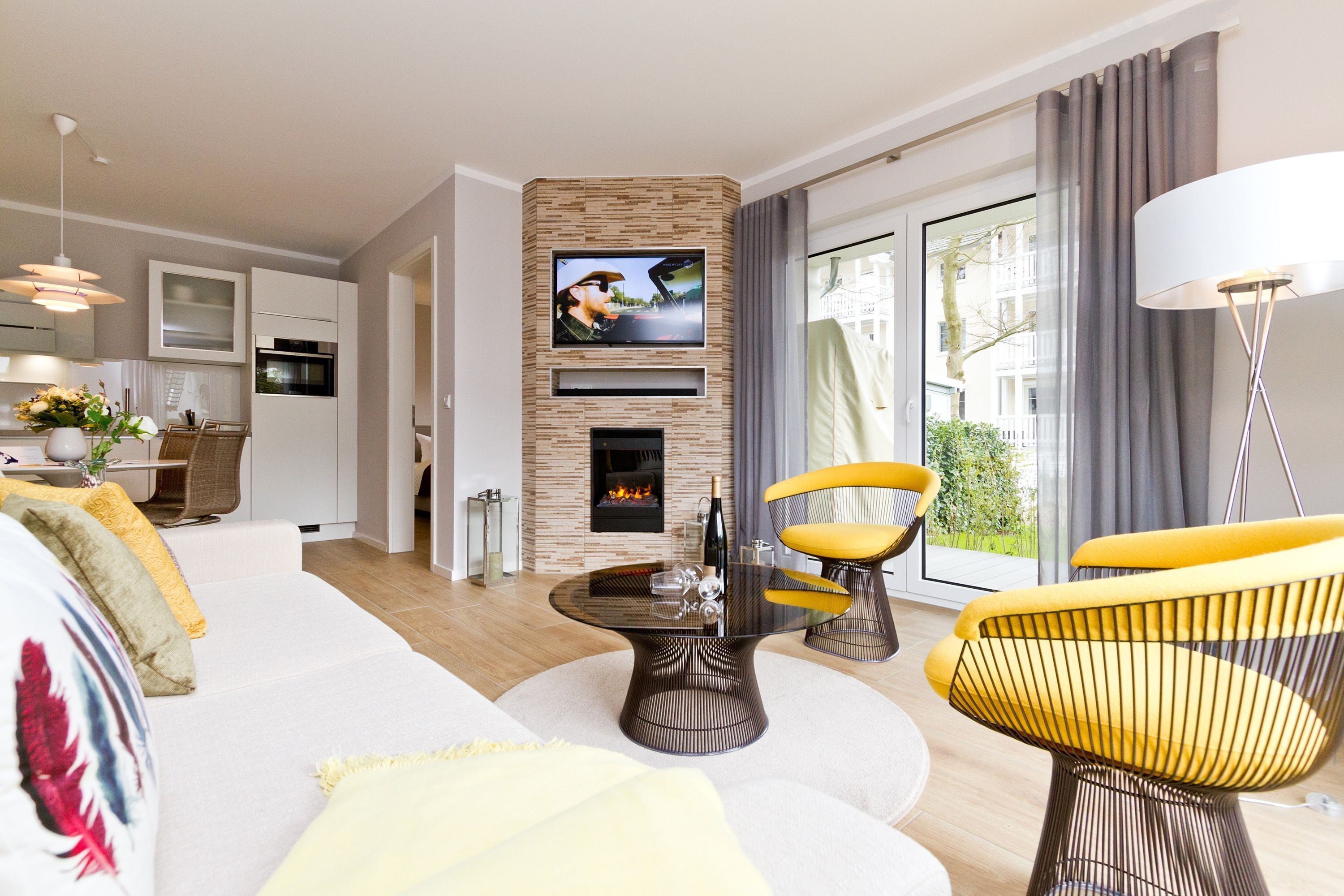 Ein modernes Wohnzimmer mit Kamin, Flachbildfernseher und Essbereich mit Tisch und Stühlen.