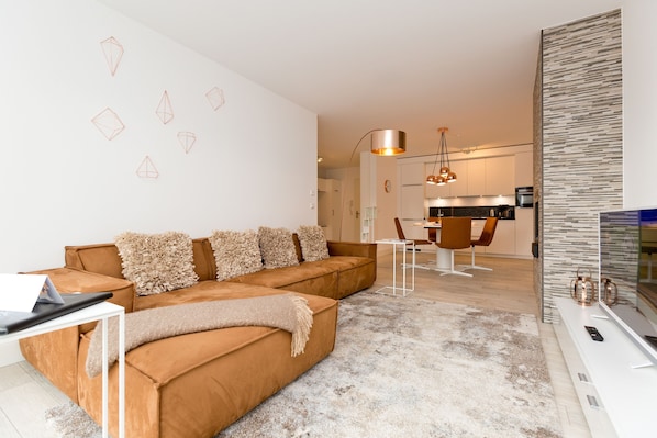 A modern living room with a brown sofa, a coffee table, and a TV stand.