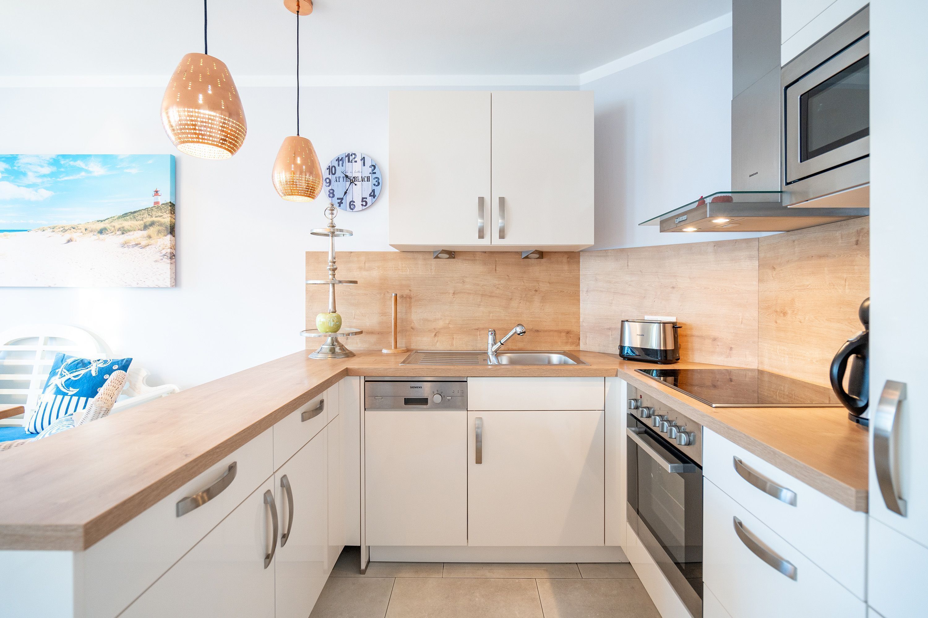 A modern kitchen with white cabinets, stainless steel appliances, and wooden countertops.