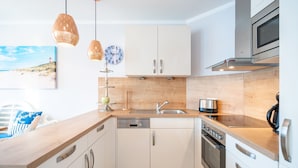 Una cocina moderna con armarios blancos, electrodomésticos de acero inoxidable y encimeras de madera.