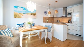 Una cocina moderna con armarios blancos, una isla de madera y lámparas colgantes.