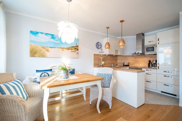 Una cocina moderna con armarios blancos, una isla de madera y lámparas colgantes.