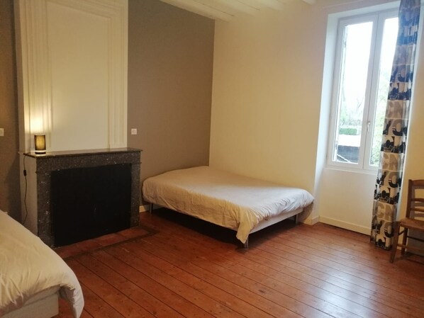 A room with a bed, a fireplace, and a window with curtains.