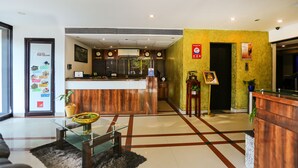 A hotel reception area with a wooden reception desk, a glass coffee table, and a black and white patterned rug. - Treebo Time Square Marine Drive (Kanayannur)
