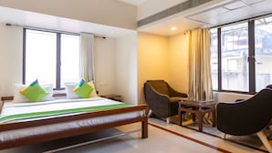 A hotel room with a bed, two chairs, a small table, and large windows. - Treebo Time Square Marine Drive (Kanayannur)