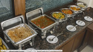 A buffet spread with various dishes and utensils. - Treebo Time Square Marine Drive (Kanayannur)