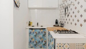 Een kleine keuken met een spoelbak, fornuis en een decoratieve spatwand.