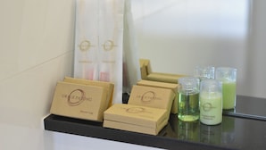 A bathroom counter with various Grace Patong toiletries including a shower cap, conditioner, and shampoo. - Grace Patong Hotel (Patong)