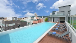 A rooftop swimming pool with lounge chairs and a city view. - Grace Patong Hotel (Patong)