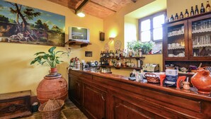 A bar area with a wooden counter, shelves with bottles, a television, and a mural on the wall. - Holiday Home Monte Santa Maria Pool Retreat (Monte sta Maria Tiberina)