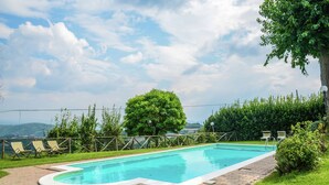 A rectangular swimming pool with a paved deck, surrounded by a wooden fence and green hedges. - Holiday Home Monte Santa Maria Pool Retreat (Monte sta Maria Tiberina)