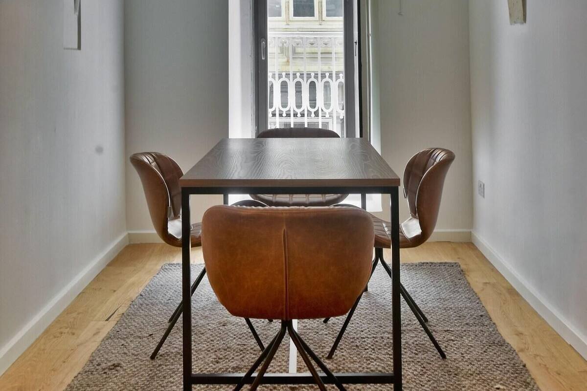 Un comedor con mesa y sillas, techo abovedado y vistas al balcón a través de una puerta.