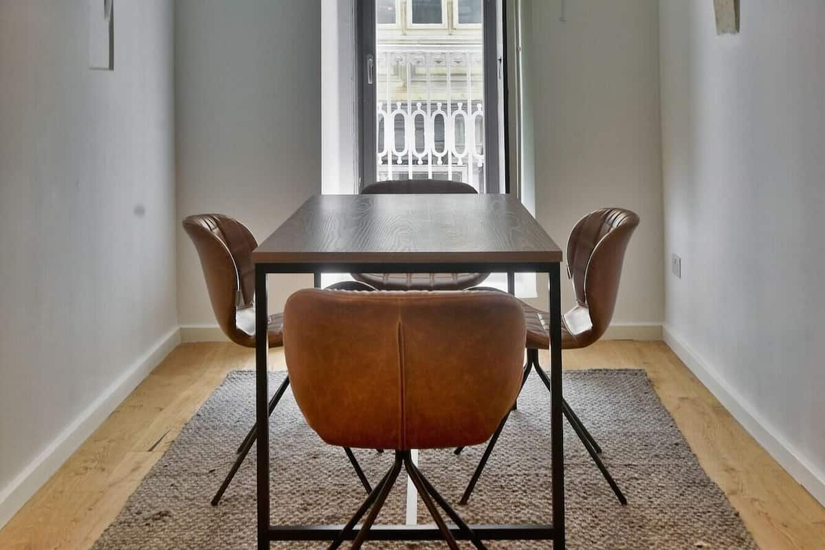 Un comedor con mesa y sillas, techo abovedado y vistas al balcón a través de una puerta.