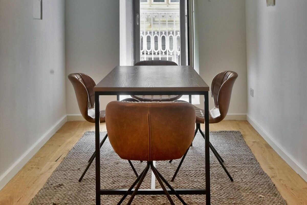 Un comedor con mesa y sillas, techo abovedado y vistas al balcón a través de una puerta.