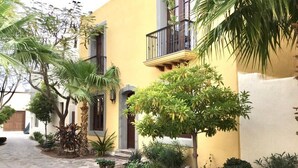 Un bâtiment jaune avec un chemin de pierre menant à une porte.