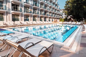 A hotel pool with sun loungers and a building with balconies in the background. - Emre Hotel And Emre Beach Hotel (Marmaris)