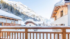 A wooden balcony railing with snow on the ground.
