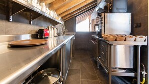 A modern kitchen with stainless steel appliances, wooden beams, and a large window.