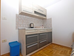 A small kitchen with a tiled backsplash, a coffee maker, and a trash bin. - Apartment 1598/16343 (Istria - Fažana), 500m from the beach (Fa žana)