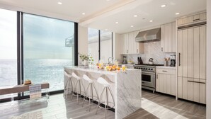 A modern kitchen with a large island, bar stools, and a view of the ocean.
