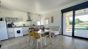 A modern kitchen with a dining area, a washing machine, and a view of a pool. - Gîte de la Picholine 3* (Ruoms)