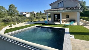 A swimming pool with a modern house in the background. - Gîte de la Picholine 3* (Ruoms)