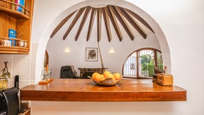 A dining area with a wooden table, a bowl of oranges, and a bookshelf with books.
