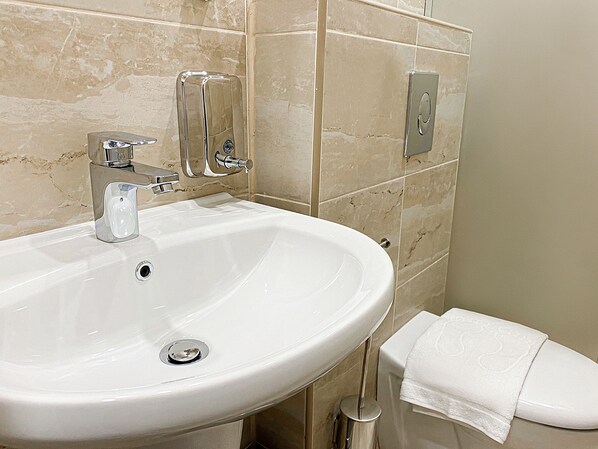 A bathroom with a white sink, chrome faucet, and a towel hanging on the wall.