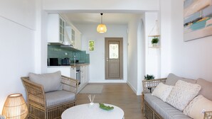 A modern living room with a round table, two wicker sofas, and a kitchen in the background. - Villa Natalia (Corfu)