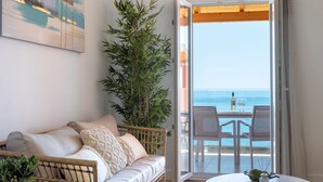 A balcony with a wicker sofa, a table, and a potted plant. - Villa Natalia (Corfu)