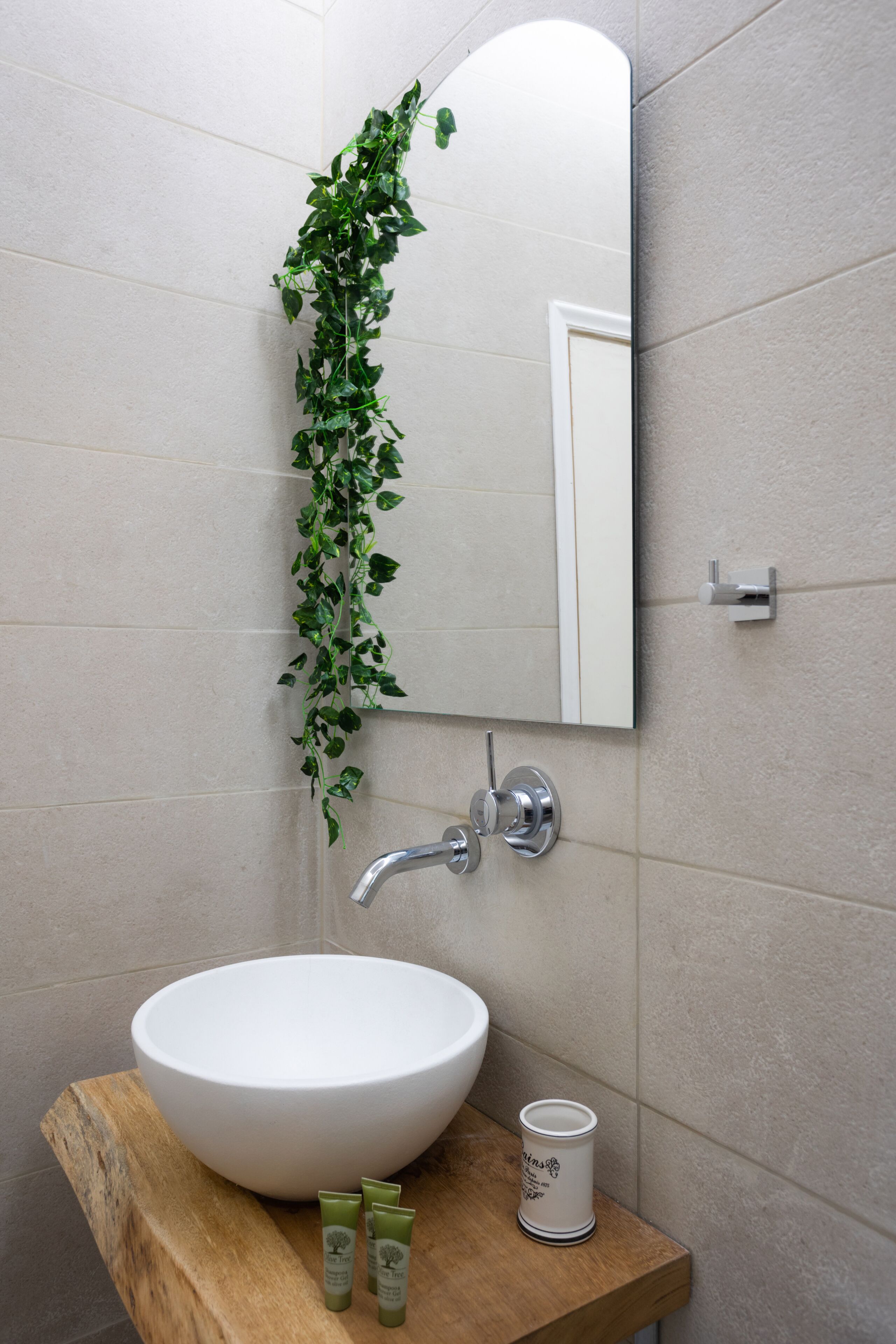 A bathroom with a white sink, a mirror, and a wooden countertop.