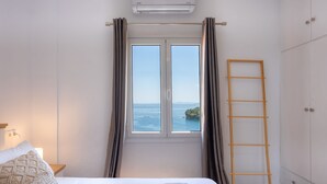A bedroom with a bed, a window with curtains, a wooden ladder, and a wardrobe. - Villa Natalia (Corfu)