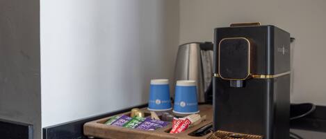 A black coffee machine with a wooden tray holding coffee pods and a coffee maker.
