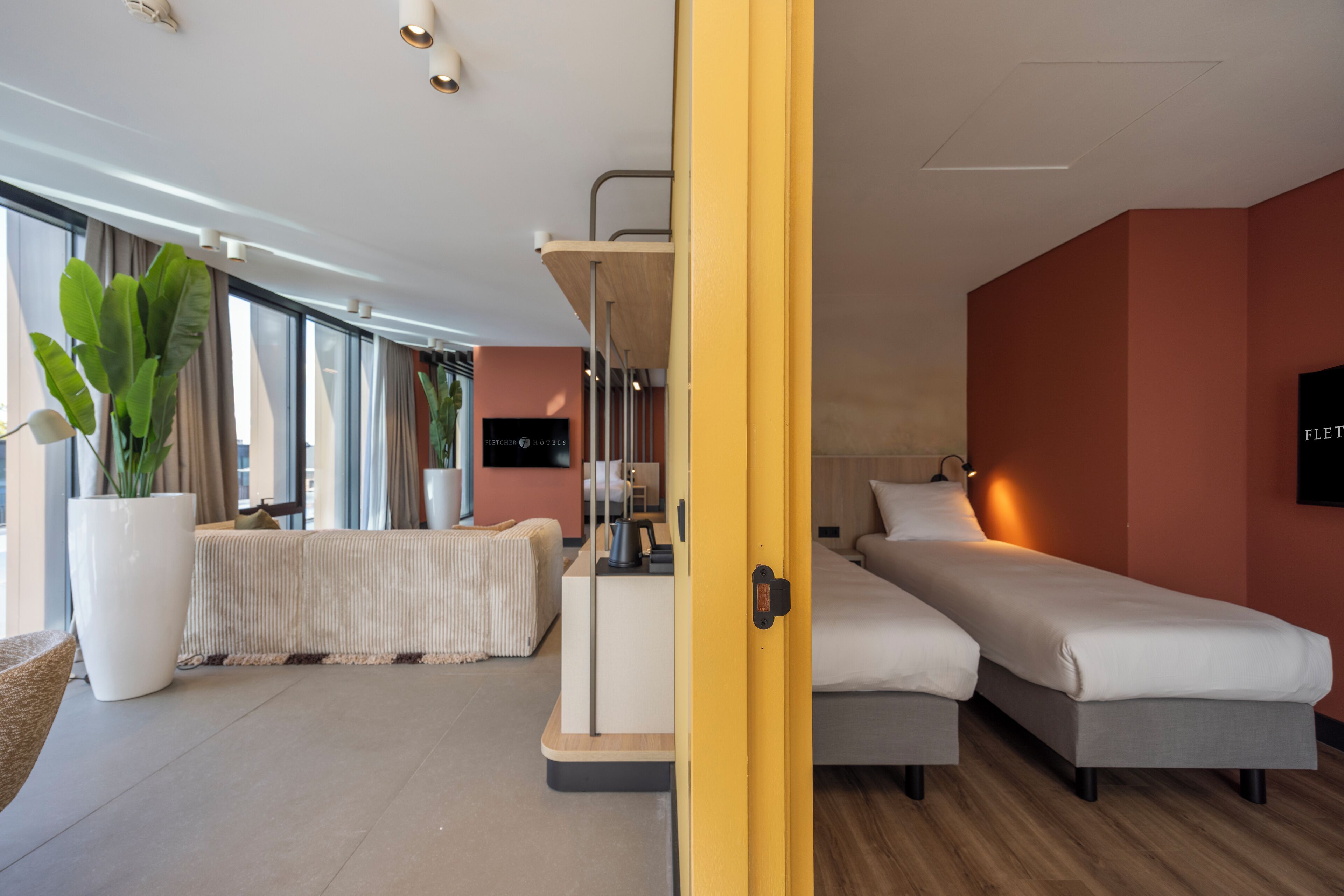 A modern hotel room with a bed, bedside table, and a large window.