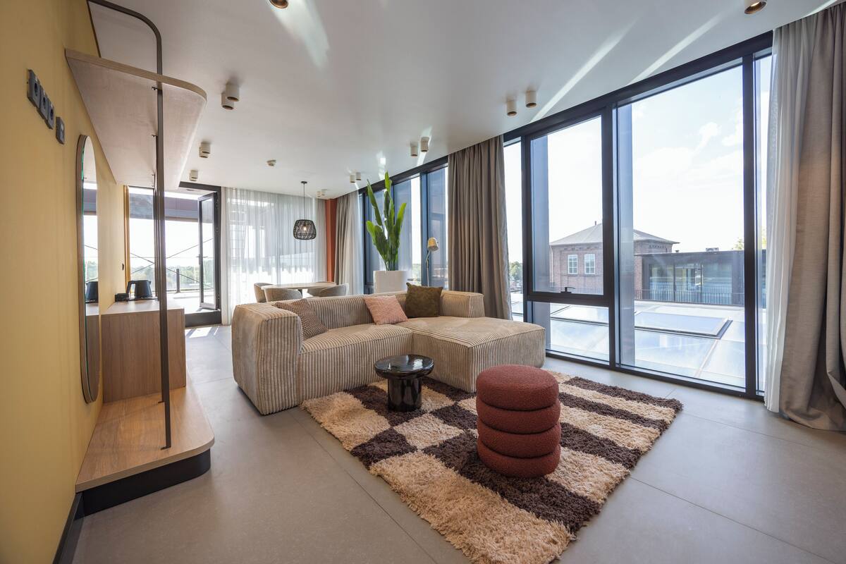 A modern living room with a large sectional sofa, a coffee table, and a potted plant.