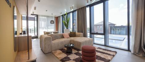 A modern living room with a large sectional sofa, a coffee table, and a potted plant.