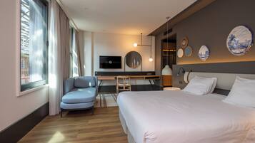 Een moderne hotelkamer met een groot bed, een bureau, een stoel en een televisie aan de muur.